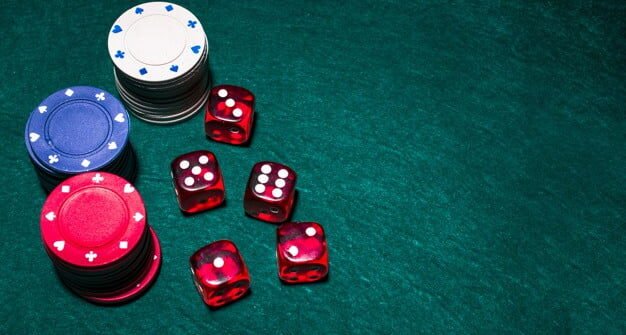 dés rouges et jetons de poker sur une table verte