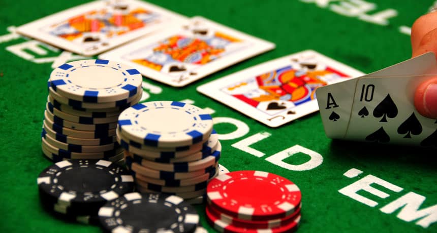 une main tenant un as et 10 à côté d'une pile de jetons de poker