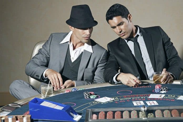 deux hommes assis devant une table de poker